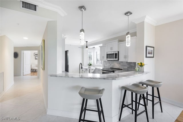 kitchen featuring a peninsula, visible vents, white cabinets, appliances with stainless steel finishes, and pendant lighting