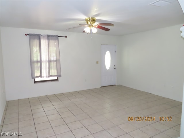 tiled empty room with ceiling fan and a wealth of natural light