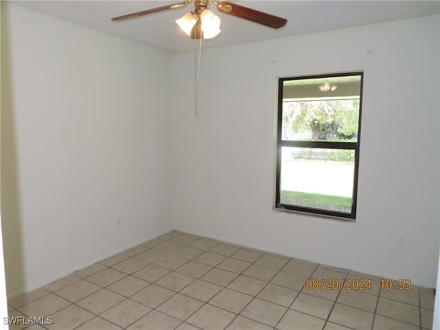 empty room featuring a wealth of natural light, light tile patterned floors, and ceiling fan