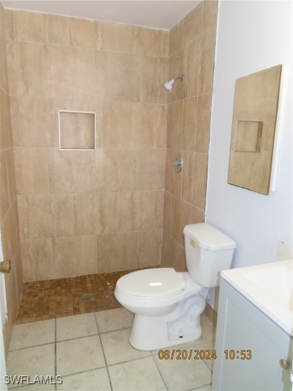 bathroom with tiled shower, tile patterned floors, toilet, and vanity