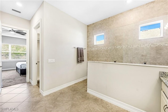 hallway featuring light tile patterned floors, baseboards, and visible vents