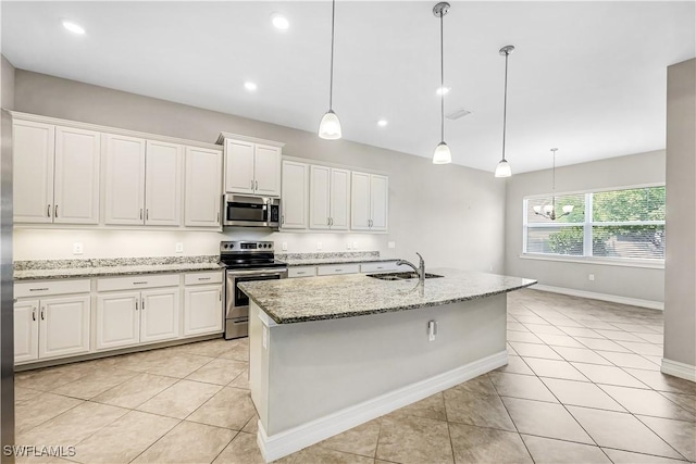 kitchen featuring light tile patterned floors, light stone counters, stainless steel appliances, a sink, and white cabinetry