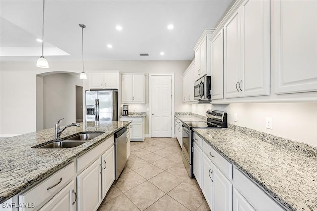 kitchen with arched walkways, stainless steel appliances, recessed lighting, white cabinetry, and a sink