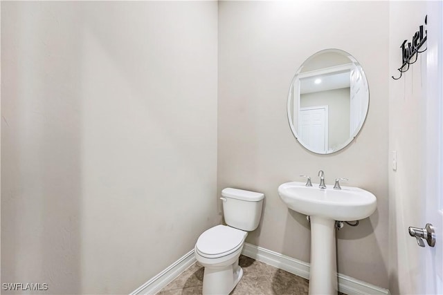 bathroom with toilet, baseboards, and tile patterned floors