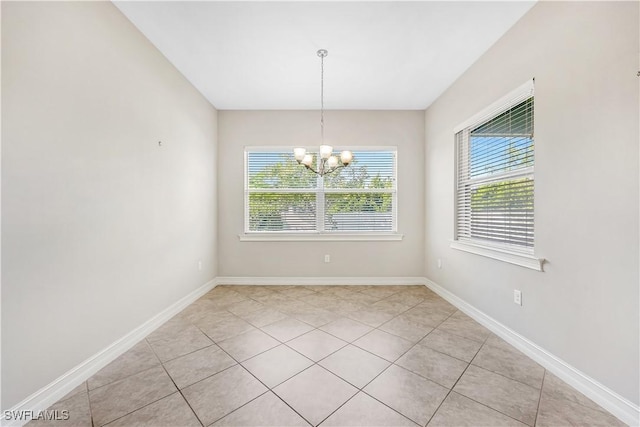 empty room with light tile patterned floors, baseboards, and a chandelier