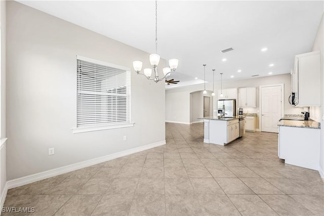 kitchen with a notable chandelier, stainless steel appliances, visible vents, baseboards, and an island with sink