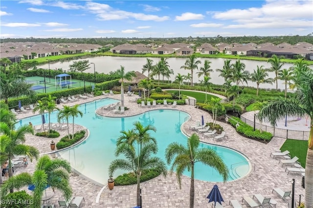 community pool featuring a patio area, a water view, fence, and a residential view