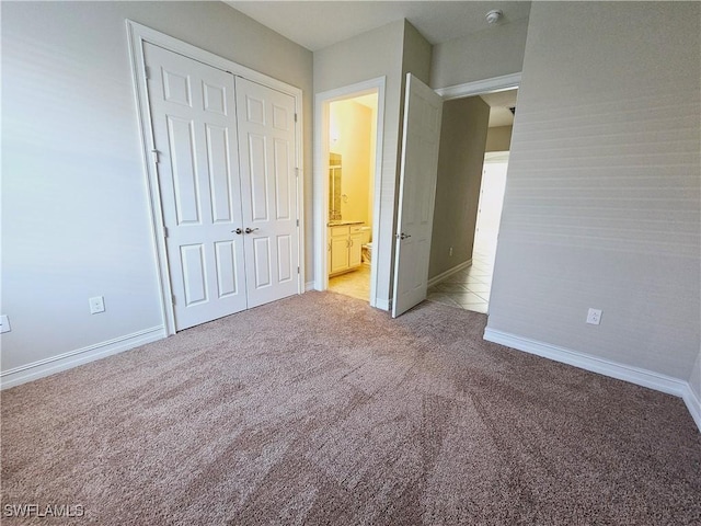 unfurnished bedroom with light carpet, a closet, and baseboards