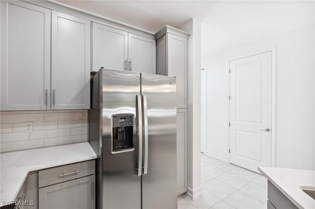 kitchen featuring tasteful backsplash, gray cabinetry, stainless steel fridge with ice dispenser, and light tile patterned floors