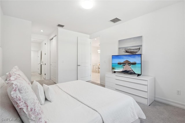 bedroom featuring light carpet and connected bathroom