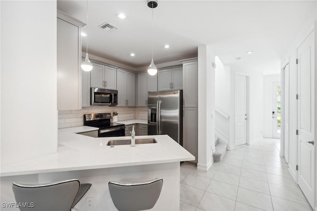 kitchen featuring appliances with stainless steel finishes, sink, a kitchen breakfast bar, kitchen peninsula, and hanging light fixtures