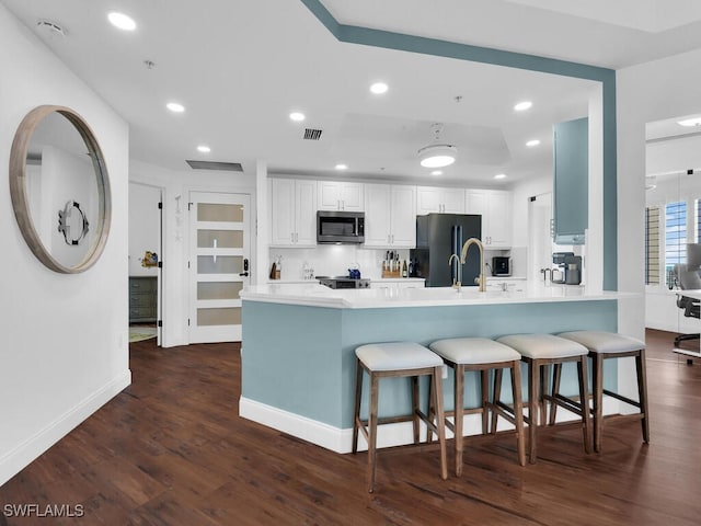 kitchen featuring kitchen peninsula, black refrigerator, white cabinetry, and dark hardwood / wood-style flooring