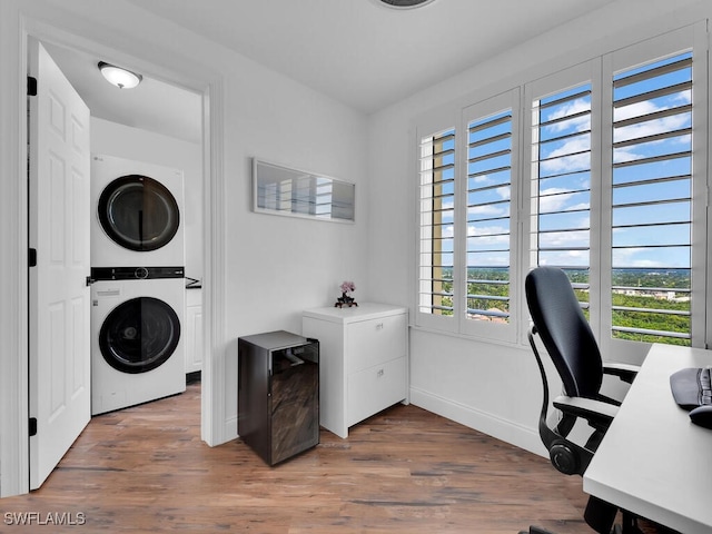 laundry room with hardwood / wood-style floors and stacked washer / dryer