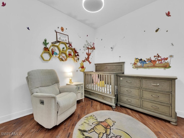 bedroom featuring wood-type flooring and a nursery area