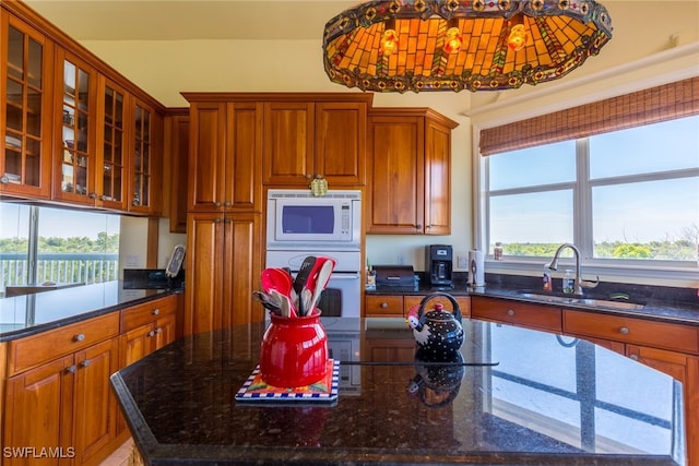 kitchen with a center island, sink, dark stone counters, and white appliances