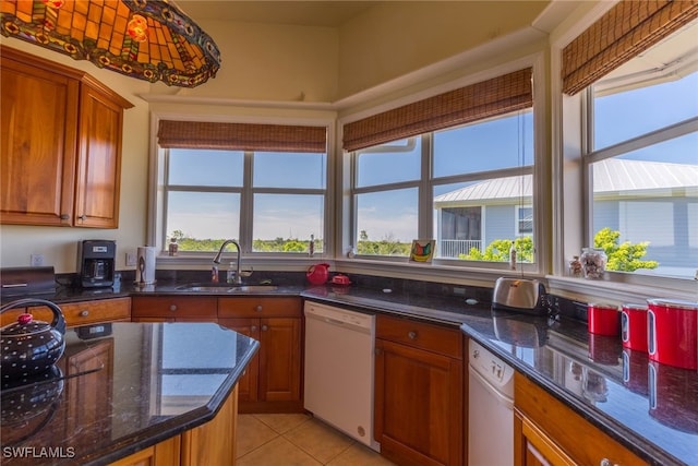 kitchen with a wealth of natural light, dark stone countertops, sink, and dishwasher