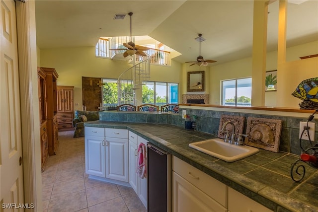 kitchen featuring sink, light tile patterned floors, ceiling fan, plenty of natural light, and white cabinets