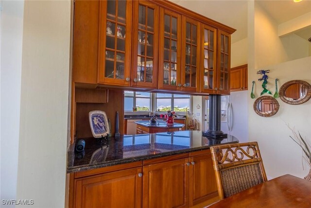 bar featuring white refrigerator with ice dispenser and dark stone counters