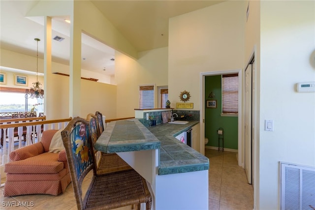 kitchen featuring sink, an inviting chandelier, decorative light fixtures, tile countertops, and light tile patterned floors