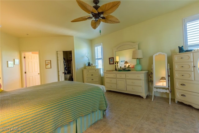 tiled bedroom with a spacious closet, a closet, ceiling fan, and multiple windows