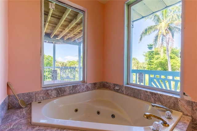 bathroom featuring tiled tub and a healthy amount of sunlight