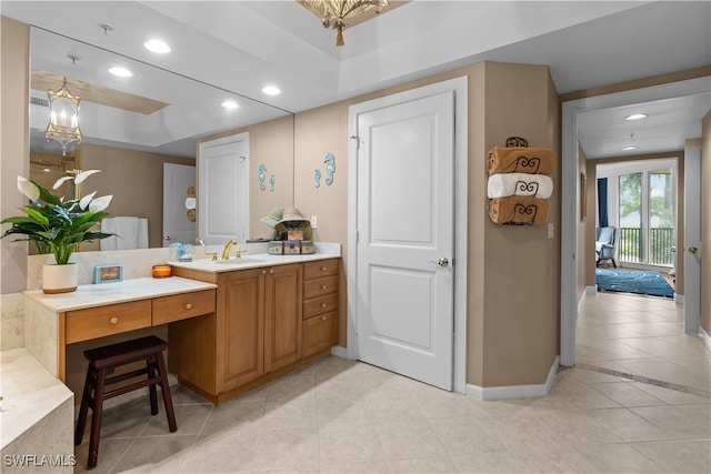 bathroom with vanity, tile patterned floors, a notable chandelier, and a raised ceiling