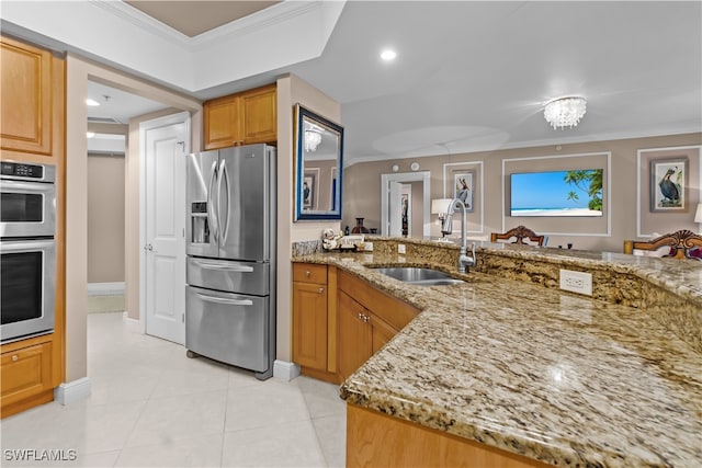 kitchen with appliances with stainless steel finishes, ornamental molding, light stone countertops, and sink