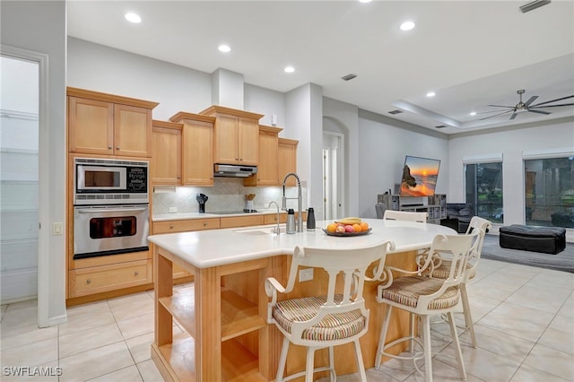 kitchen with built in microwave, light tile patterned floors, oven, a kitchen breakfast bar, and ceiling fan