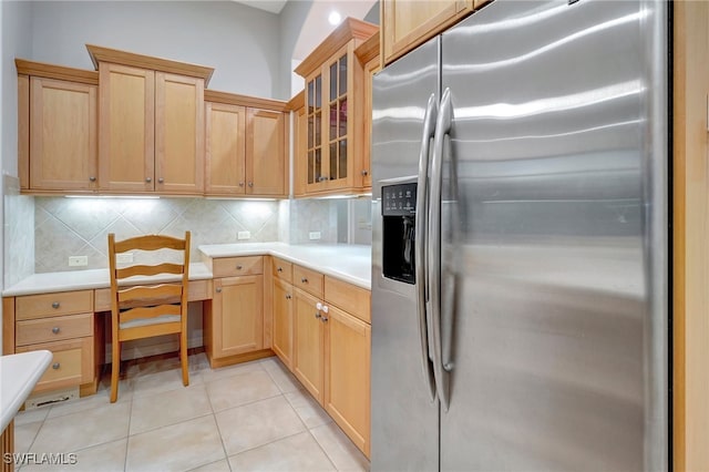 kitchen featuring light tile patterned floors, stainless steel fridge, light brown cabinets, and tasteful backsplash