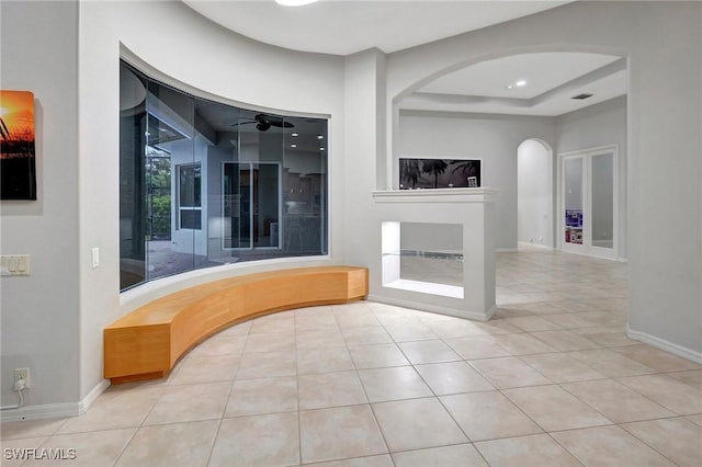 15120 Blackhawk Dr, Fort Myers, FL 33912 - unfurnished living room with arched walkways, tile patterned flooring, a ceiling fan, a tray ceiling, and a fireplace