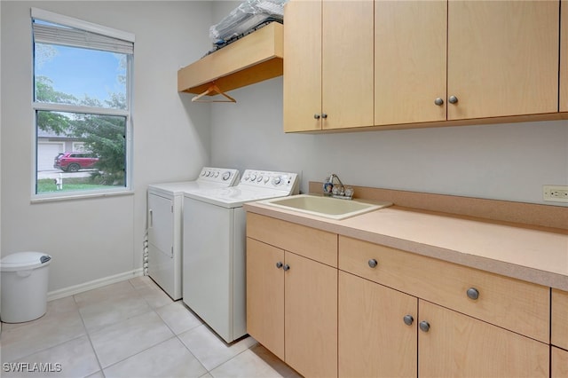 clothes washing area featuring cabinets, independent washer and dryer, light tile patterned floors, and sink