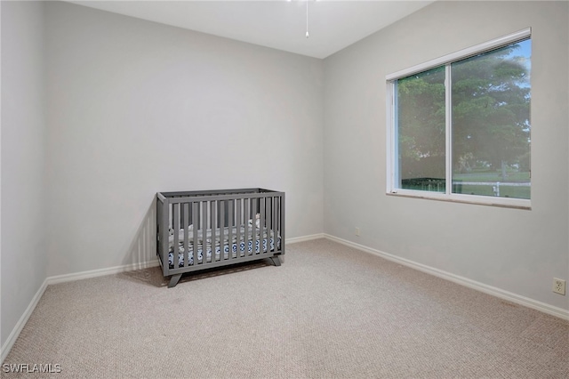 unfurnished bedroom with carpet flooring, multiple windows, and a crib