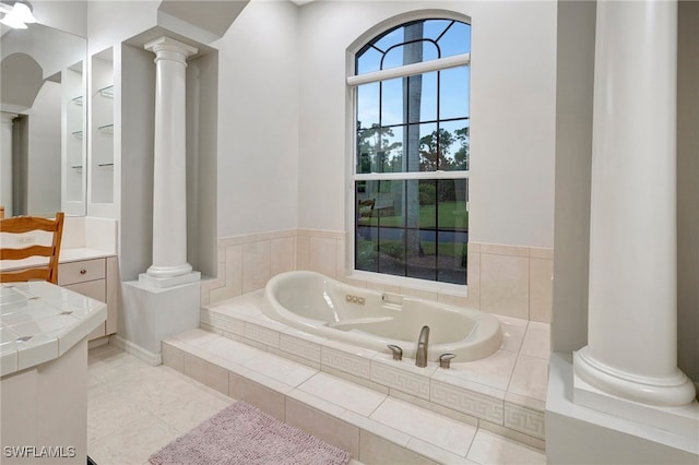 bathroom featuring vanity, a relaxing tiled tub, and ornate columns