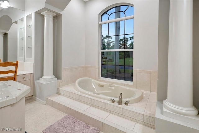 full bath featuring tile patterned flooring, ornate columns, and a bath