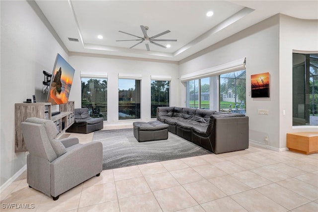 tiled living room featuring ceiling fan and a raised ceiling