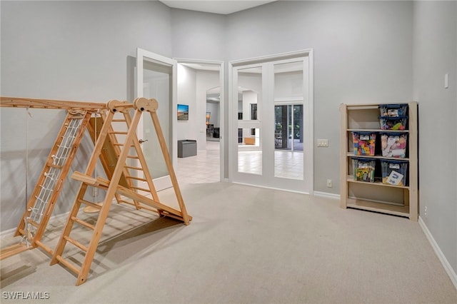 interior space featuring a towering ceiling, light carpet, and french doors