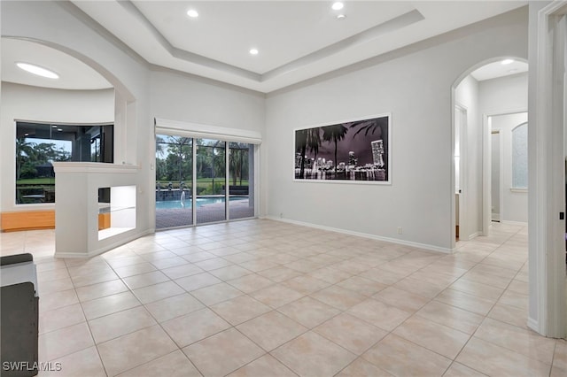 unfurnished living room featuring a raised ceiling and light tile patterned flooring