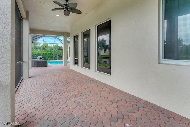 view of patio / terrace featuring a ceiling fan, glass enclosure, and an outdoor pool