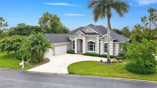 view of front of property featuring a garage, concrete driveway, a front yard, and stucco siding