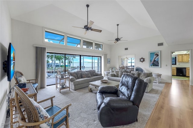 living room featuring ceiling fan, high vaulted ceiling, and light hardwood / wood-style flooring