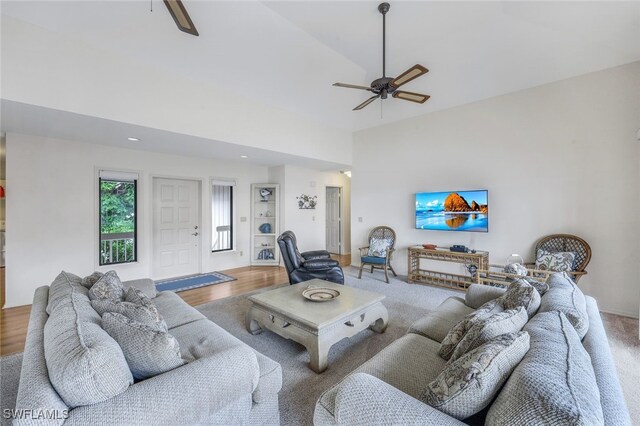 living room with ceiling fan, hardwood / wood-style flooring, and a towering ceiling