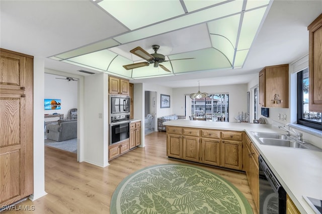 kitchen featuring sink, light wood-type flooring, ceiling fan, black appliances, and kitchen peninsula