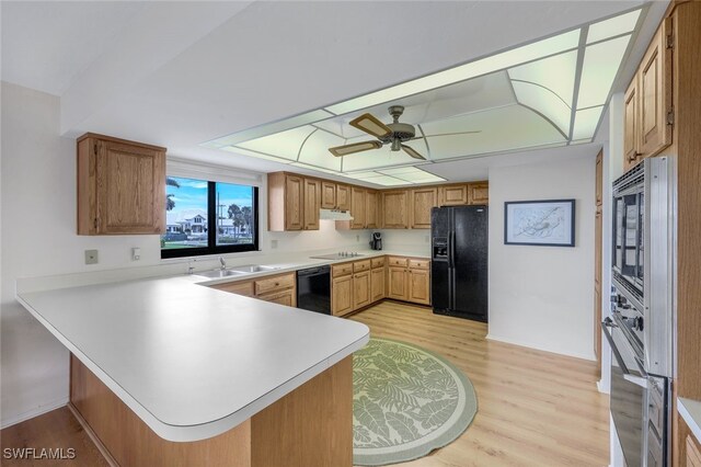 kitchen with sink, black appliances, light wood-type flooring, kitchen peninsula, and ceiling fan