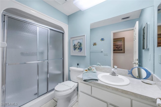 bathroom featuring tile patterned flooring, a shower with door, vanity, and toilet