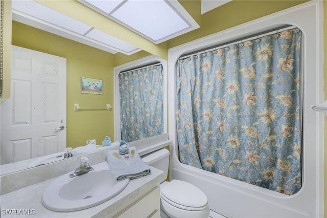 full bathroom with shower / tub combo with curtain, vanity, a skylight, and toilet