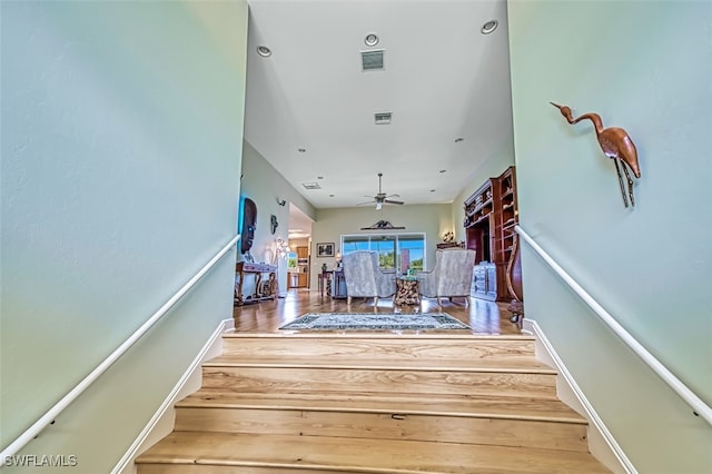 stairway featuring ceiling fan and hardwood / wood-style flooring