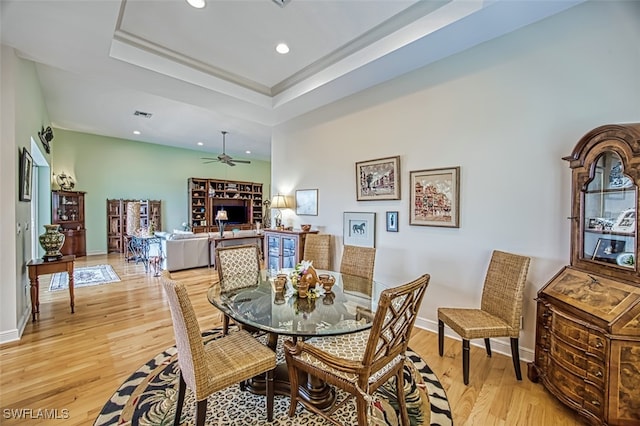 dining area featuring light hardwood / wood-style flooring, ceiling fan, and a tray ceiling