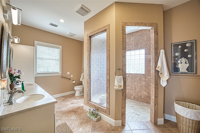 bathroom featuring tiled shower, toilet, a wealth of natural light, and vanity