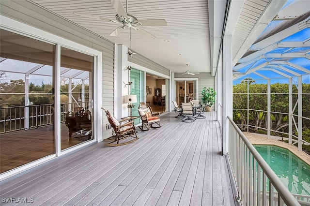 wooden terrace with glass enclosure, a ceiling fan, and an outdoor pool