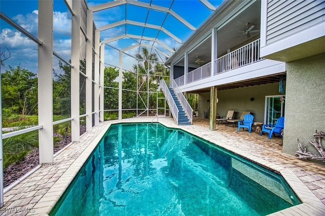 outdoor pool with a ceiling fan, a lanai, a patio area, and stairway